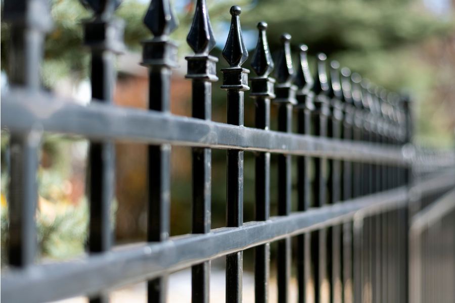 A run of black ornamental iron fencing with vertical pickets